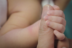 Photo of a baby hand wrapped around an adult thumb